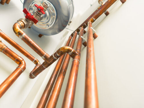 copper pipes along a white wall